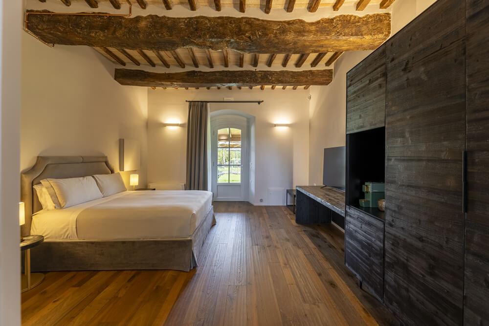 Camera accogliente con travi a vista, letto soffice e luce calda.