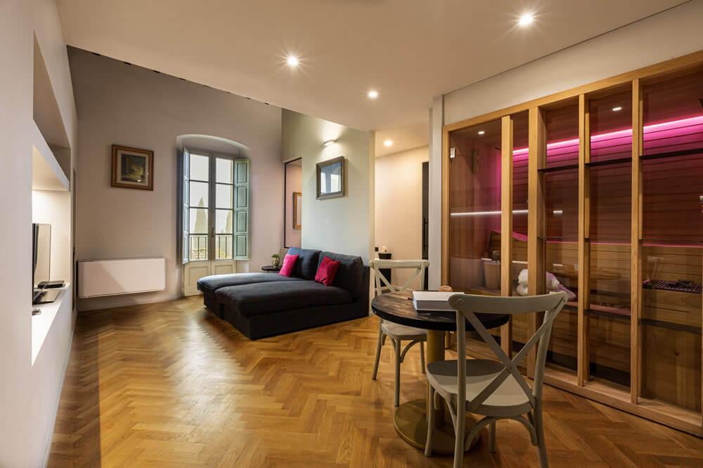 Elegante soggiorno con parquet, divano accogliente e sauna luminosa.
