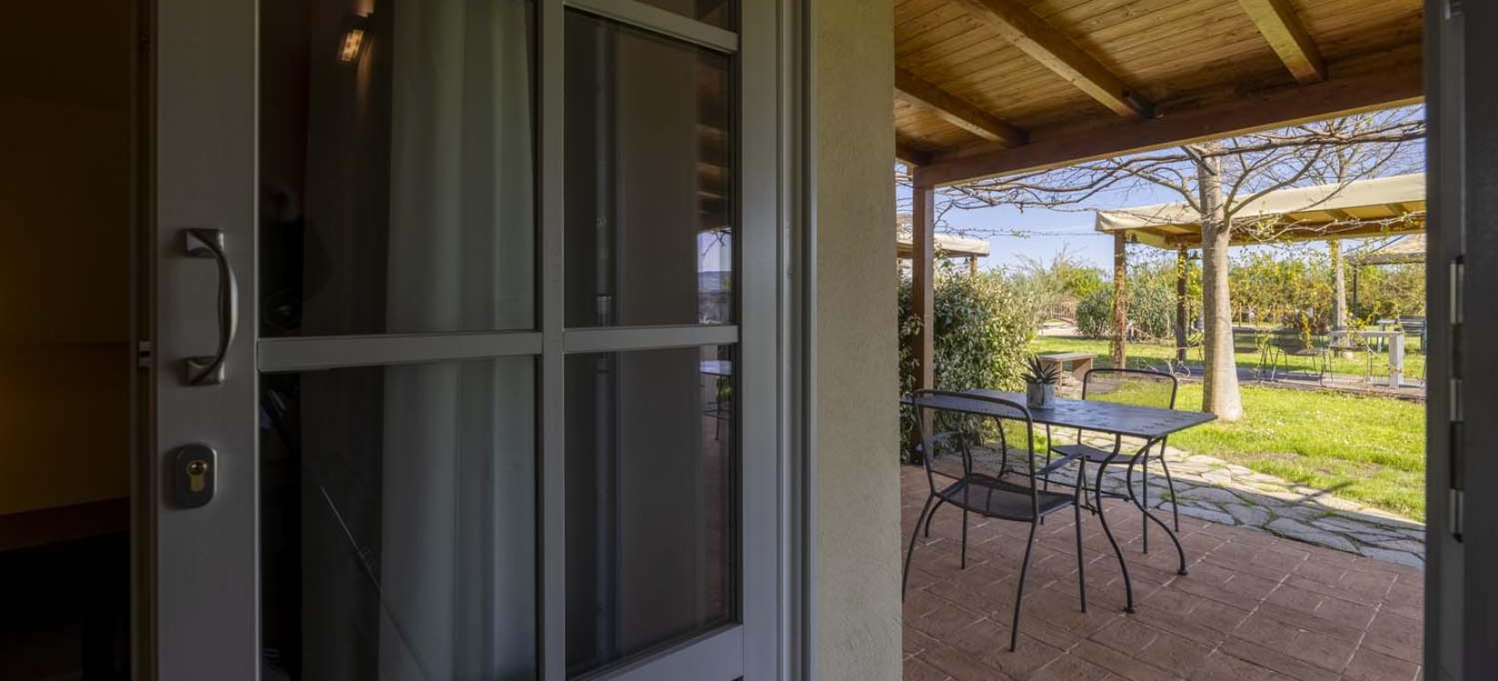 Open door to a sunny garden, table and chairs inviting relaxation.